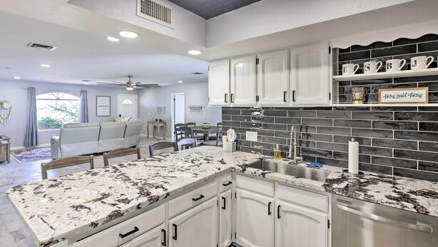 A modern kitchen with white cabinetry, a granite countertop, and a black backsplash. - Heated Pool: Home ~ 5 Mi to Lake Havasu! (Lake Havasu City)