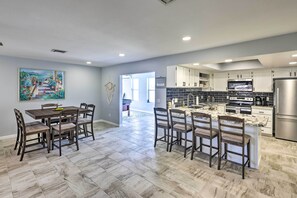 A modern kitchen with white cabinets, a stainless steel refrigerator, and a dining area with a marble table and chairs. - Heated Pool: Home ~ 5 Mi to Lake Havasu! (Lake Havasu City)