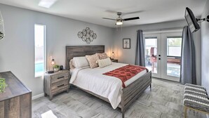 A bedroom with a bed, bedside tables, a ceiling fan, a window, and a view of the outside. - Heated Pool: Home ~ 5 Mi to Lake Havasu! (Lake Havasu City)