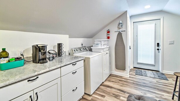 A compact kitchen with a coffee maker, a kettle, and a toaster. There is a white washing machine and a small table with a mat. - Fayetteville Apartment w/ Yard: Pets Welcome! (Fayetteville)