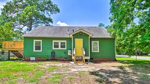 A green house with a yellow door, a small porch, and a wooden deck. - Fayetteville Apartment w/ Yard: Pets Welcome! (Fayetteville)
