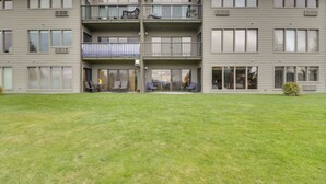 A multi-story residential building with balconies, large windows, and a well-maintained lawn. - Bigfork Condo w/ Hot Tub Access, By Lake! (Bigfork)