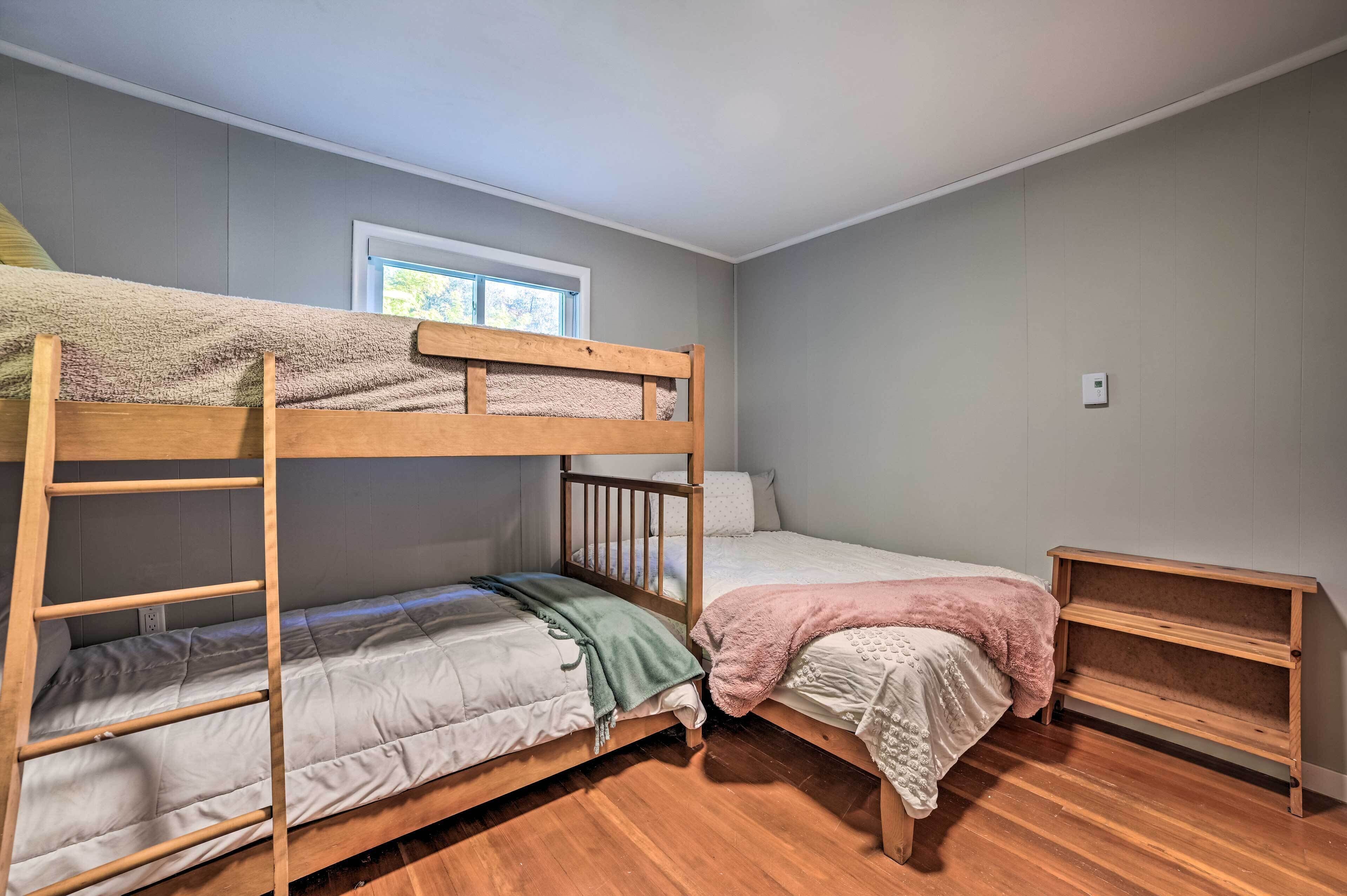 A bunk bed room with a window, a wooden shelf, and a thermostat on the wall.