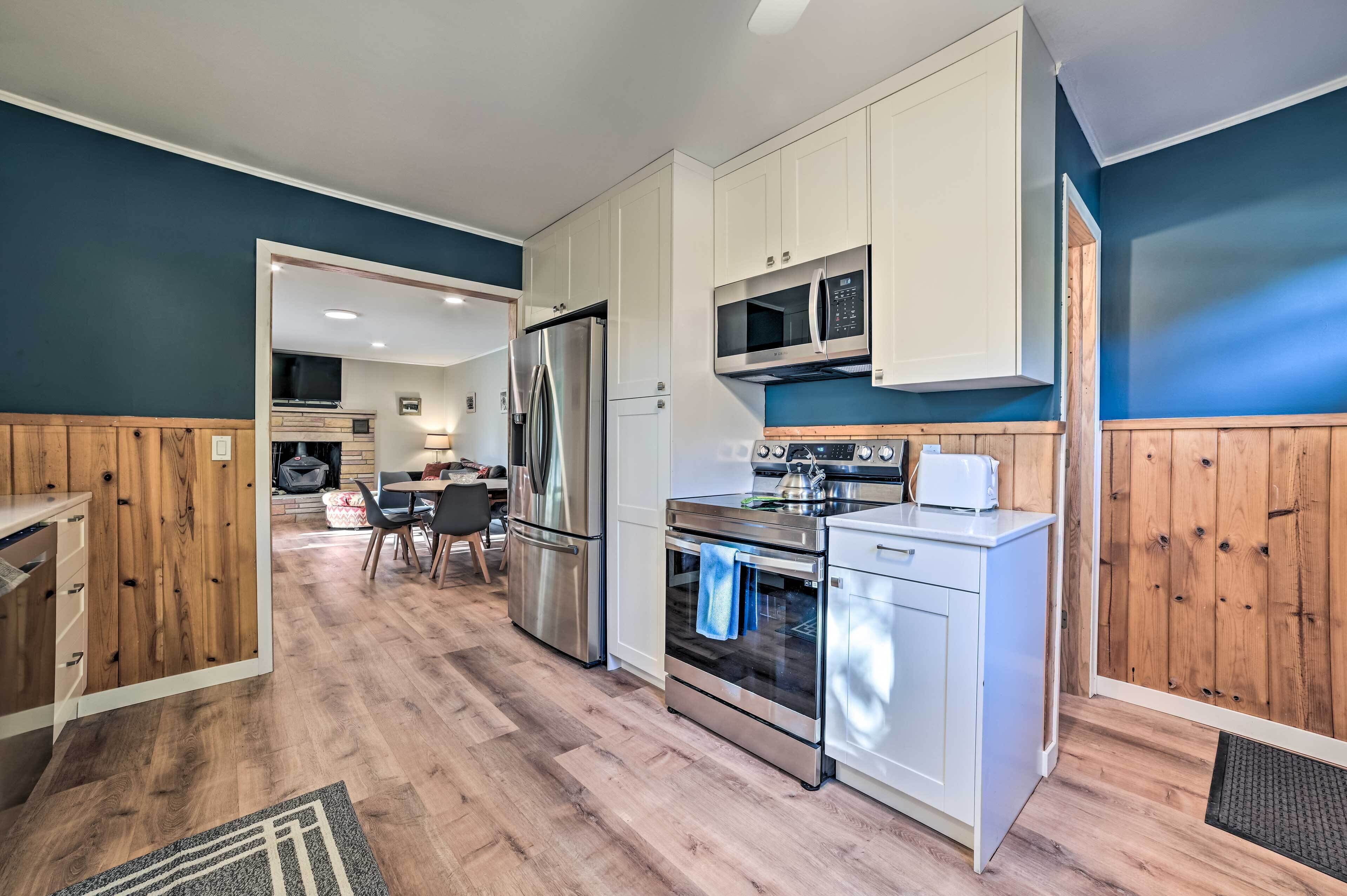A modern kitchen with white cabinets, stainless steel appliances, and a wooden floor.