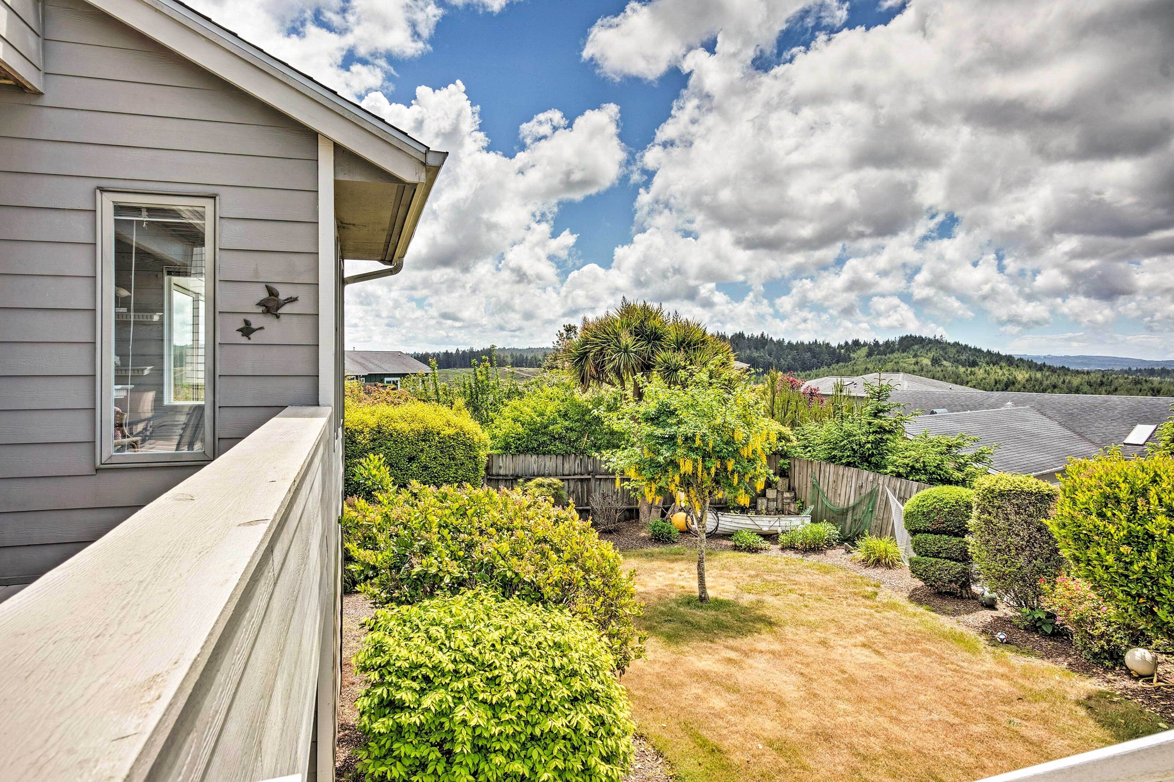 A residential property with a well-maintained garden, a wooden fence, and a clear view of the surrounding landscape.