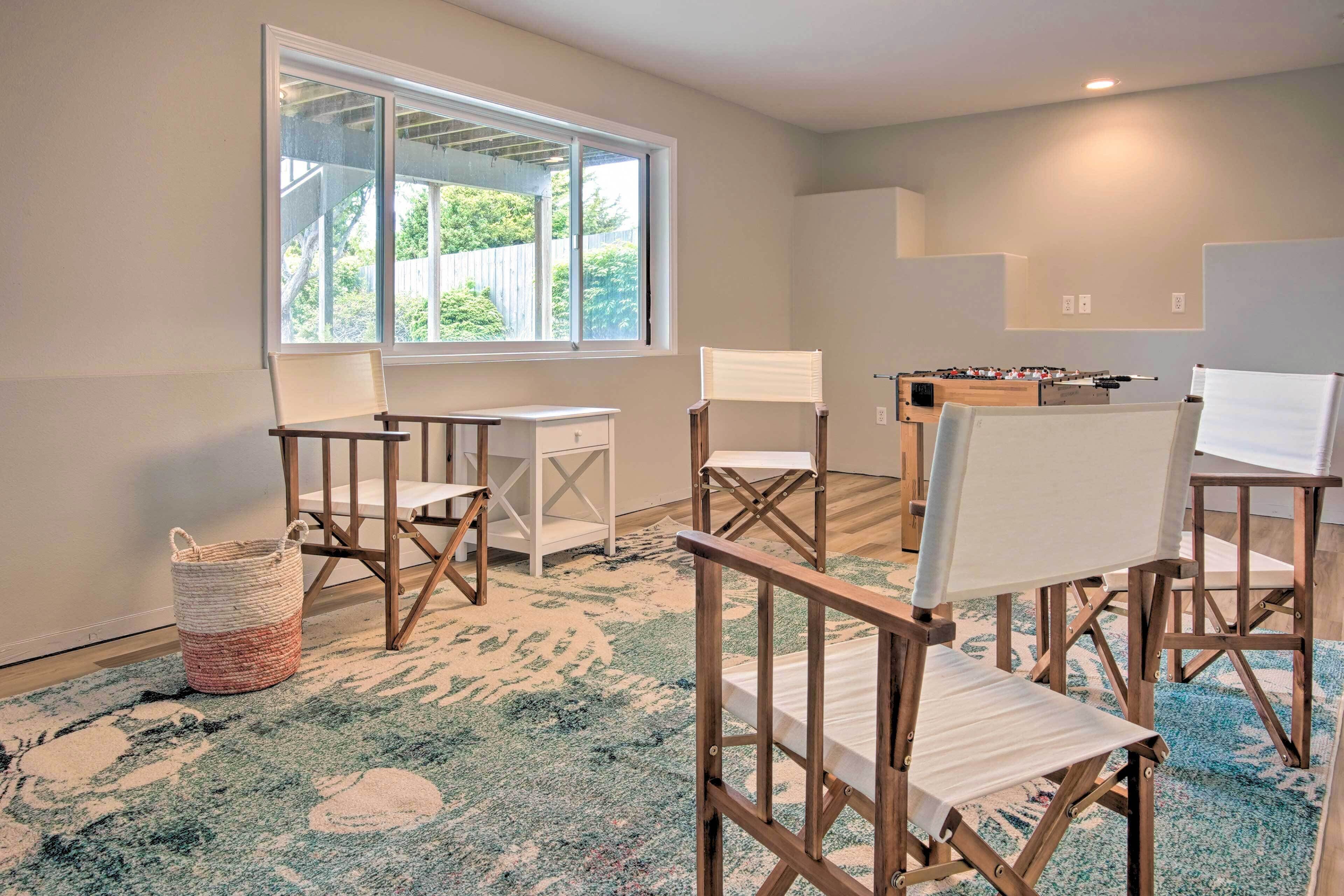 A room with a large window, a foosball table, and several foldable chairs.