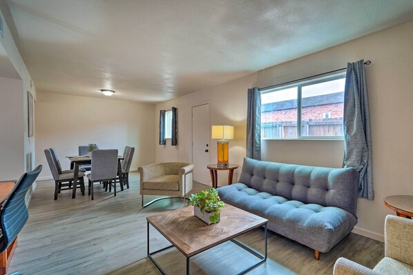A modern living room with a sofa, dining table, chairs, and a coffee table with a plant. - Odessa Apartment w/ Proximity to Attractions! (Odessa)