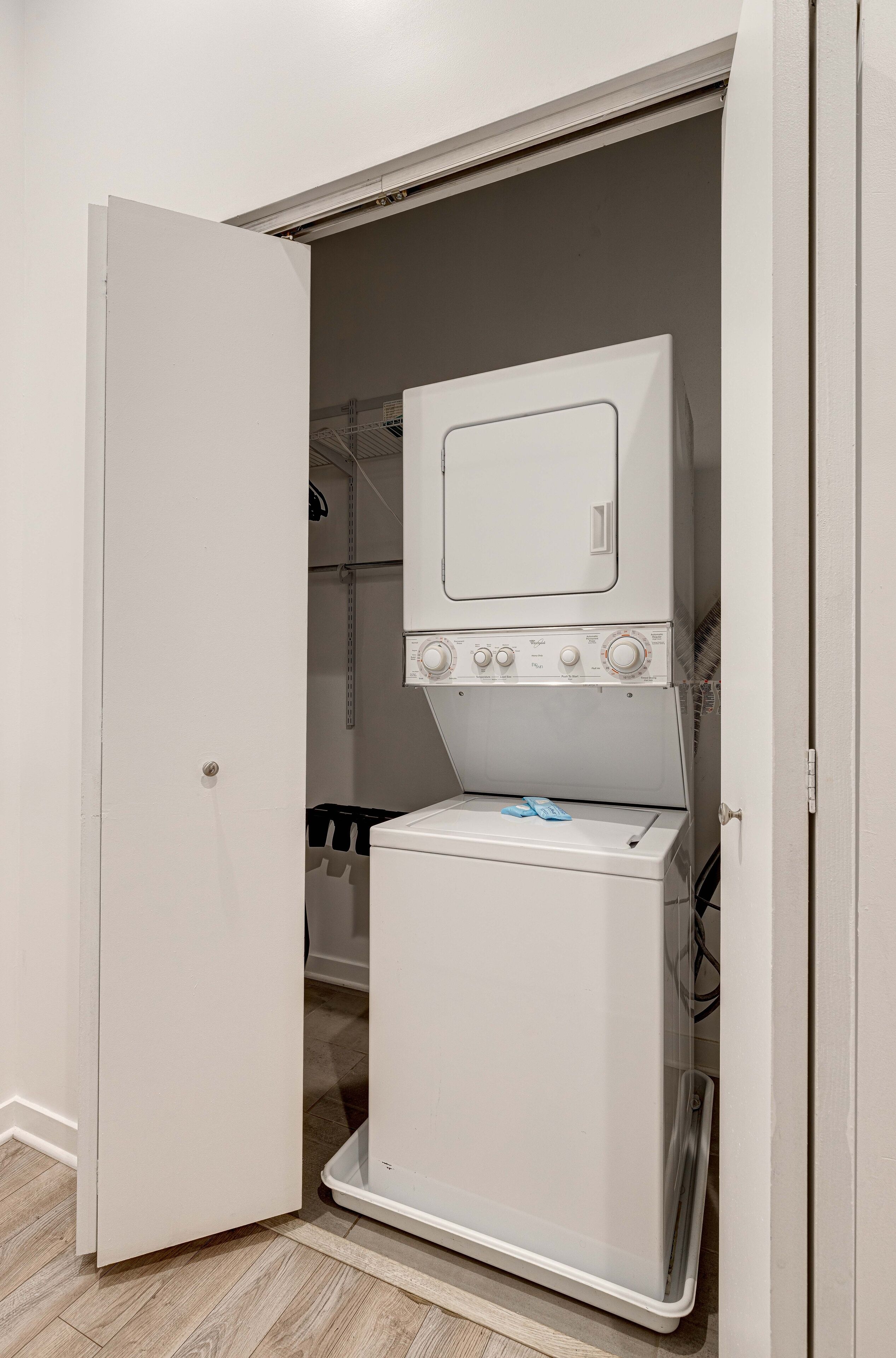 Een wasserette met een voorlader wasmachine en droger, een deur en een plank in de achtergrond.