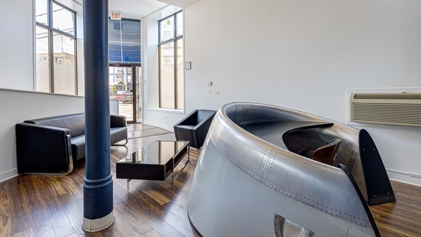 A modern interior with a large metallic chair, a glass table, and a black sofa. - Cabin 105 by 747 Lofts (Chicago)