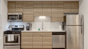 A modern kitchen with wooden cabinets, stainless steel appliances, and a tiled backsplash. - Cabin 105 by 747 Lofts (Chicago)