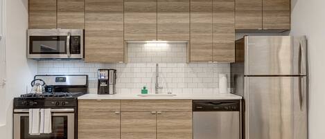 A modern kitchen with wooden cabinets, stainless steel appliances, and a tiled backsplash.
