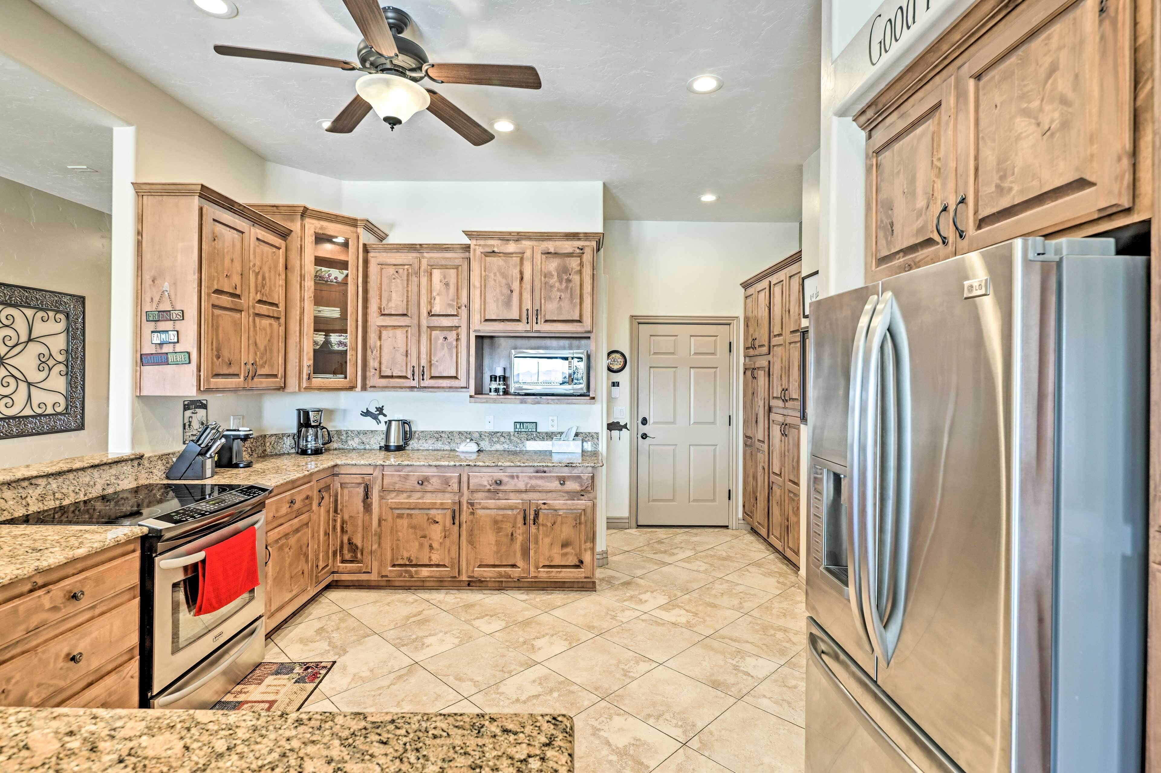 A kitchen with wooden cabinets, granite countertops, stainless steel appliances, and a ceiling fan.