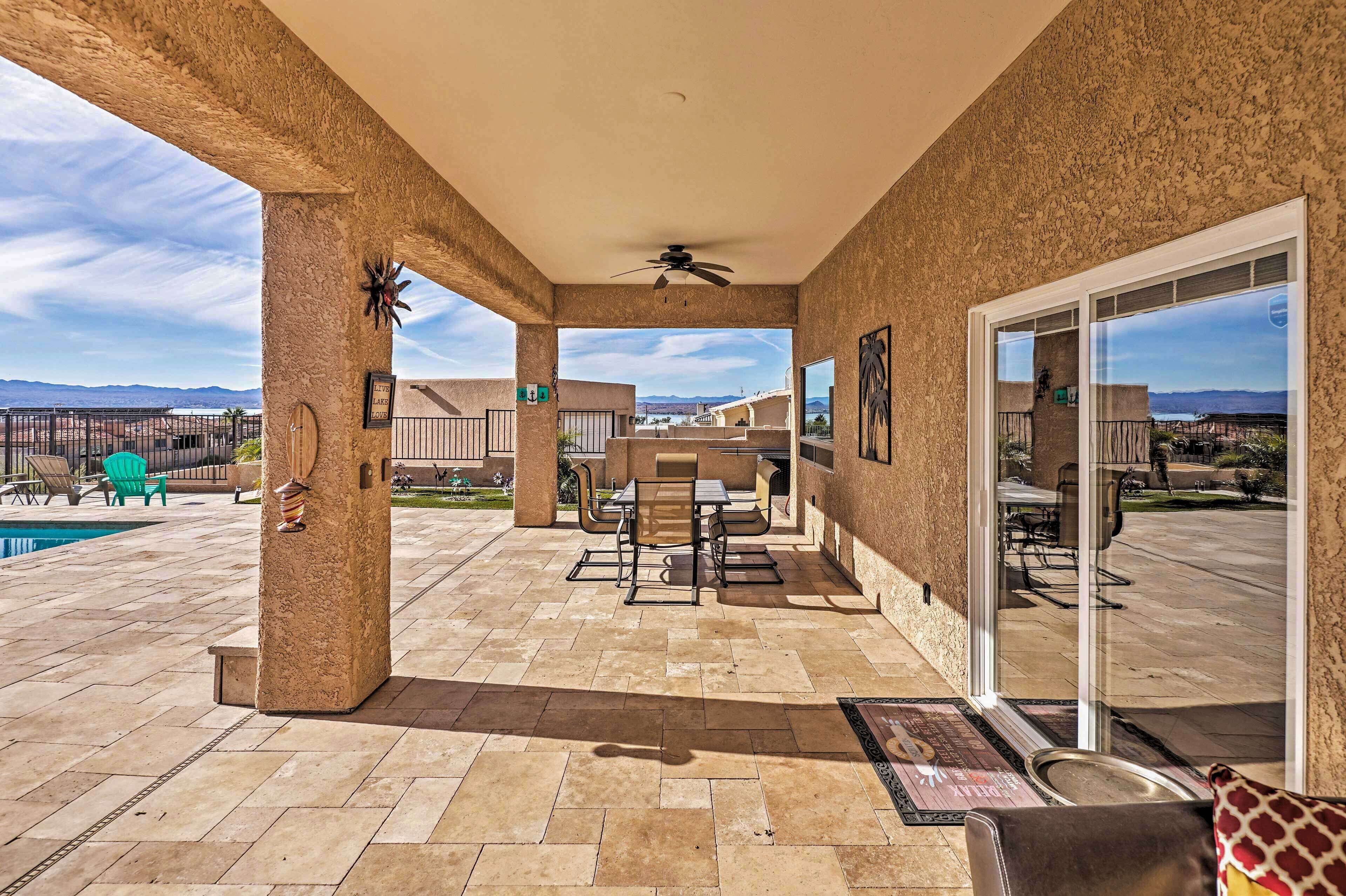A covered patio area with a pool, outdoor seating, and a view of the mountains.