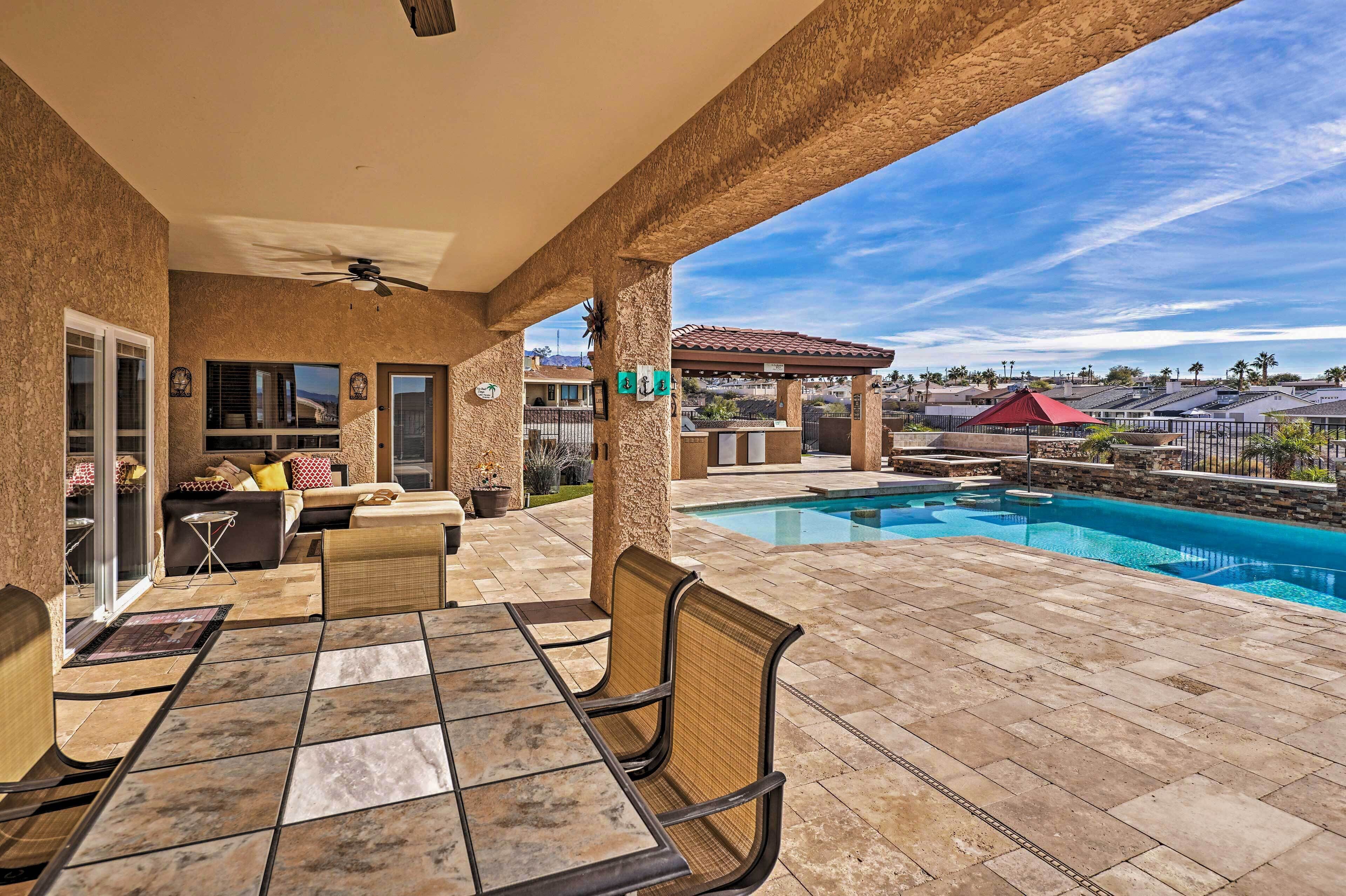 A covered patio with a pool, outdoor seating, and a view of the surrounding area.
