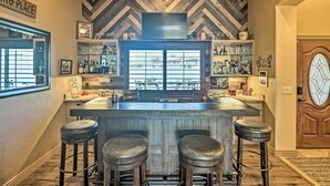 A bar area with a herringbone-patterned ceiling, a large window, and a wooden door. - Luxe Retreat w/ Lake Havasu View & Pool! (Lake Havasu City)