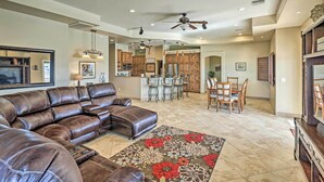 A spacious living room with a brown leather sectional sofa, a dining area with wooden chairs, and a kitchen in the background. - Luxe Retreat w/ Lake Havasu View & Pool! (Lake Havasu City)