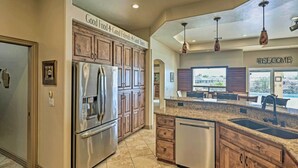 A modern kitchen with stainless steel appliances, wooden cabinets, and a granite countertop. - Luxe Retreat w/ Lake Havasu View & Pool! (Lake Havasu City)
