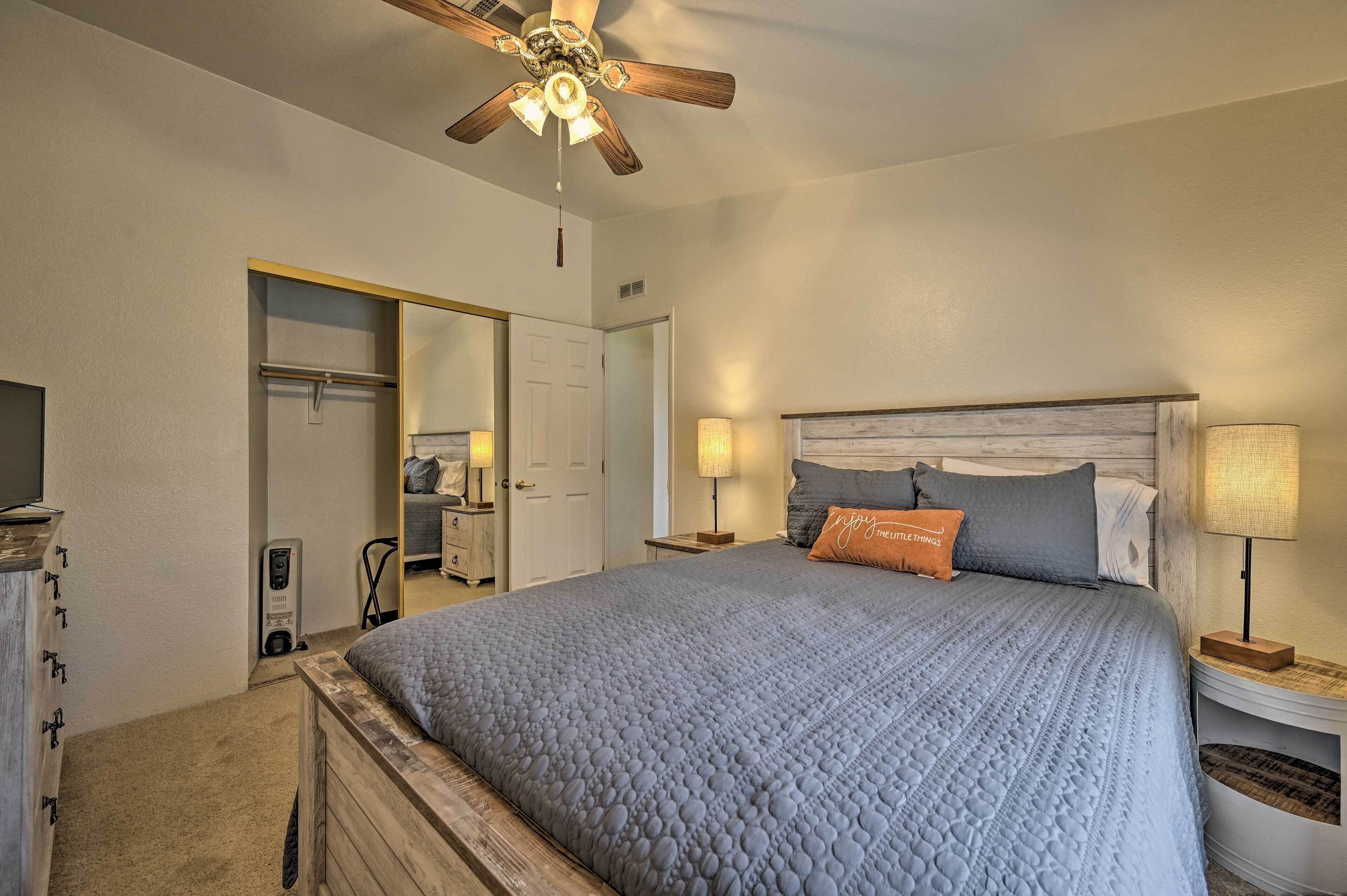 A bedroom with a large bed, a ceiling fan, bedside lamps, and a wardrobe.