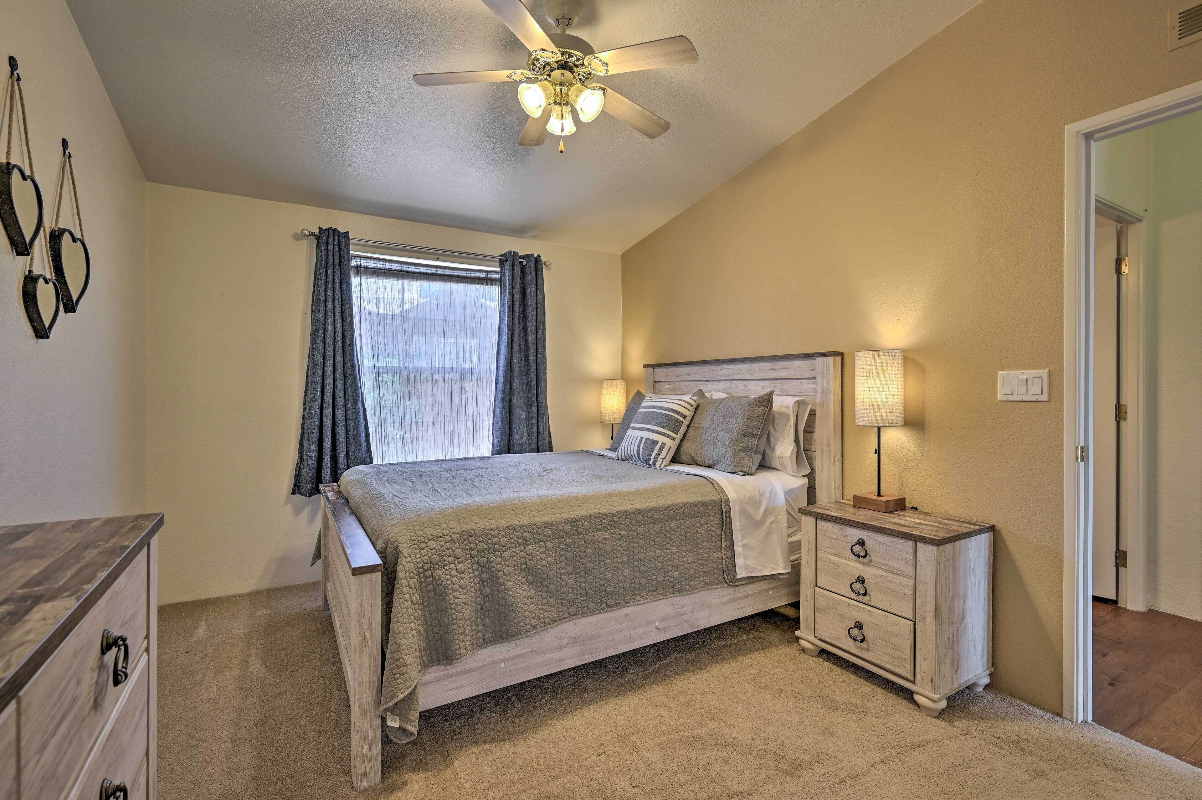 A bedroom with a bed, nightstand, and ceiling fan.