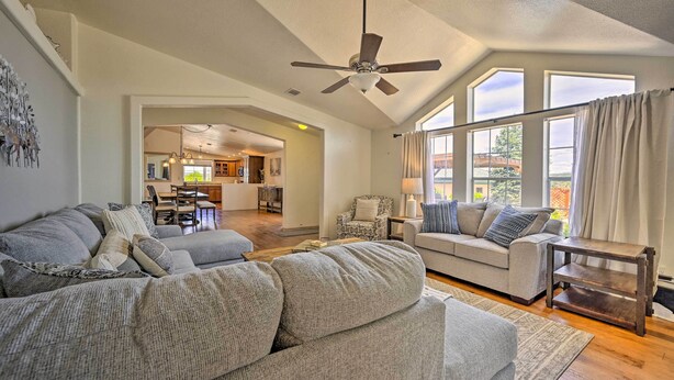 A spacious living room with a high ceiling fan, large windows, and a view of the kitchen. - Arizona Room, Gas Grill: Charming Payson Home! (Payson)