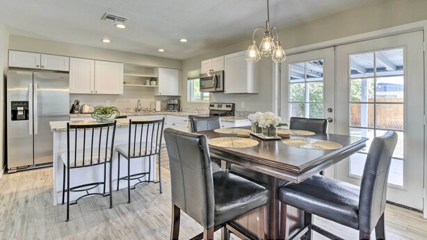 A modern kitchen with white cabinets, stainless steel appliances, and a dining area with a wooden table and leather chairs. - 3 Mi to Asu! Snowbird Poolside Escape in Tempe (Tempe)