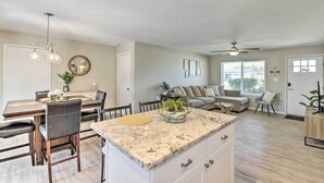 A modern kitchen with a granite countertop, dining area with a table and chairs, and a living room with a sofa and a coffee table. - 3 Mi to Asu! Snowbird Poolside Escape in Tempe (Tempe)