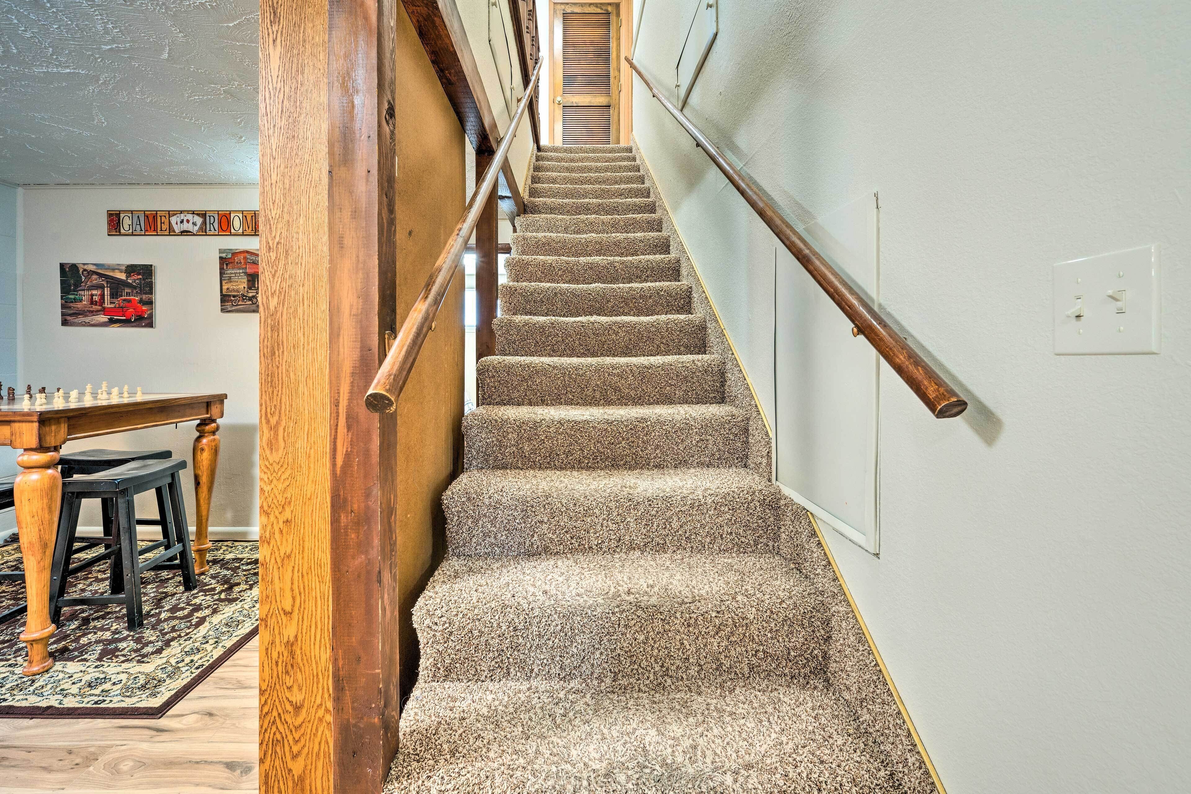 A carpeted staircase with wooden handrails, a dining area with a chessboard, and a wall with a 'GAME ROOM' sign.