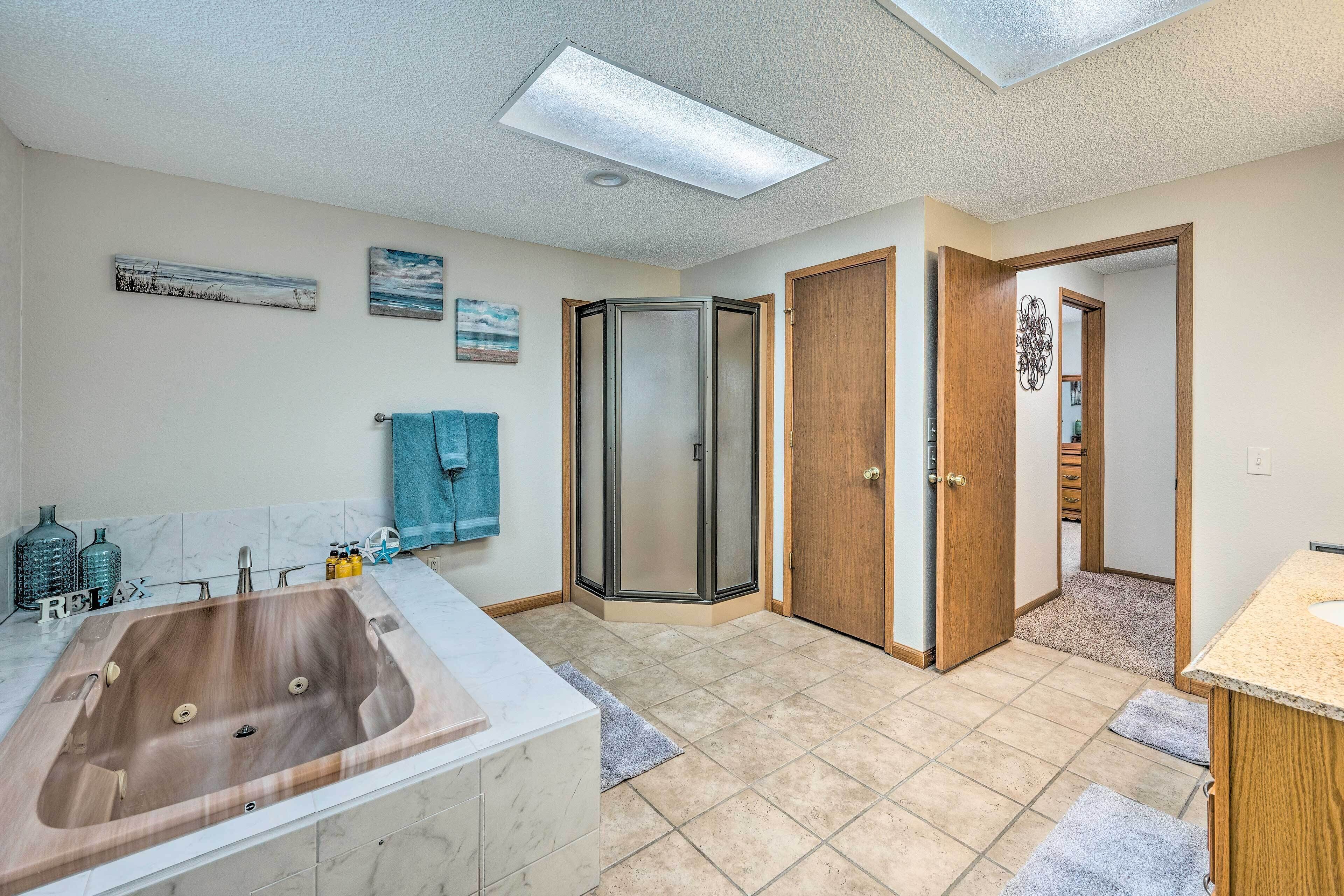 A bathroom with a large wooden bathtub, a walk-in shower, and a wooden door leading to another room.