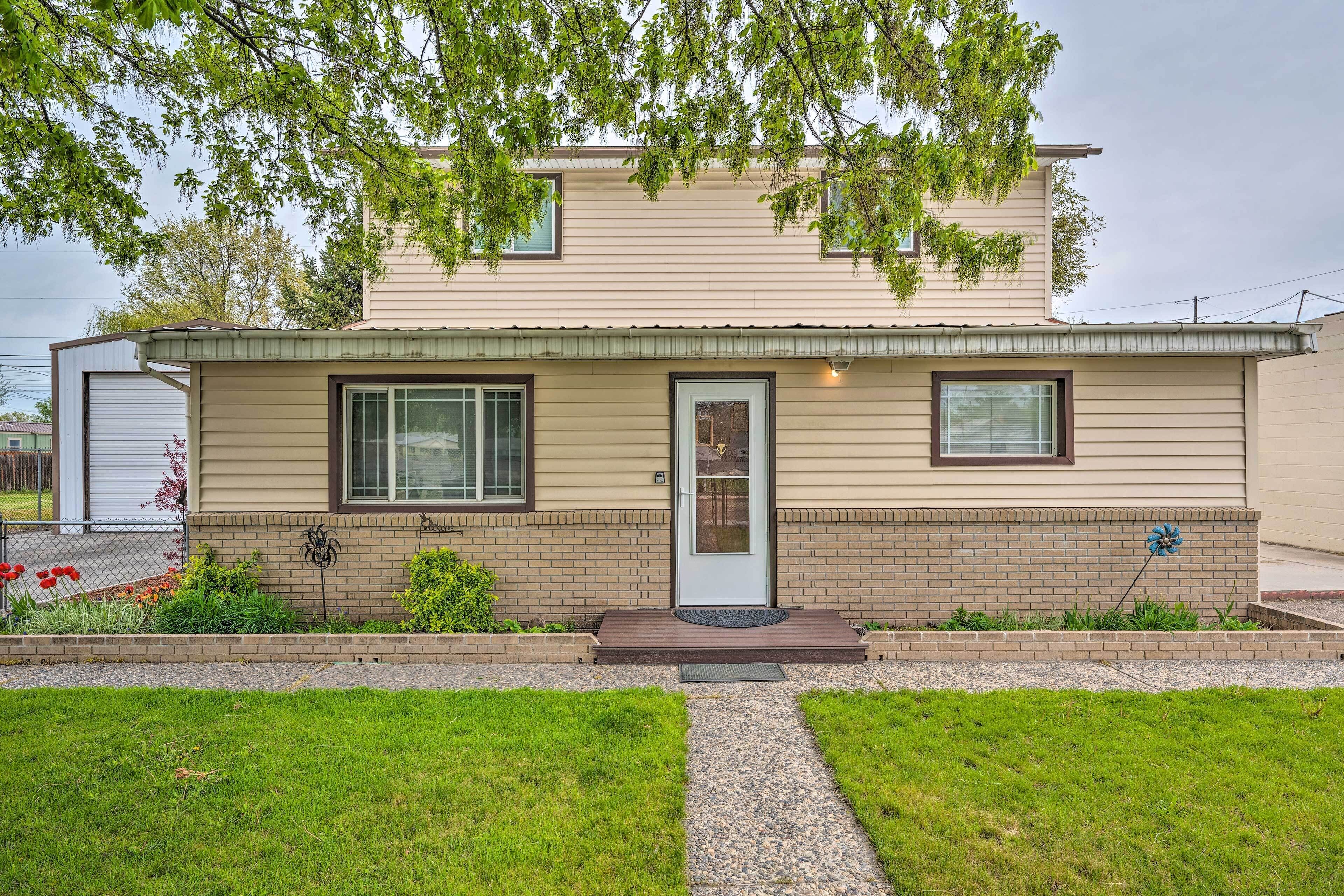 A two-story house with a front porch, a brick foundation, and a small garden area.