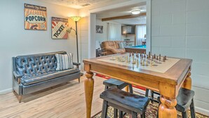 A living room with a chess table, a sofa, and two wall decorations.