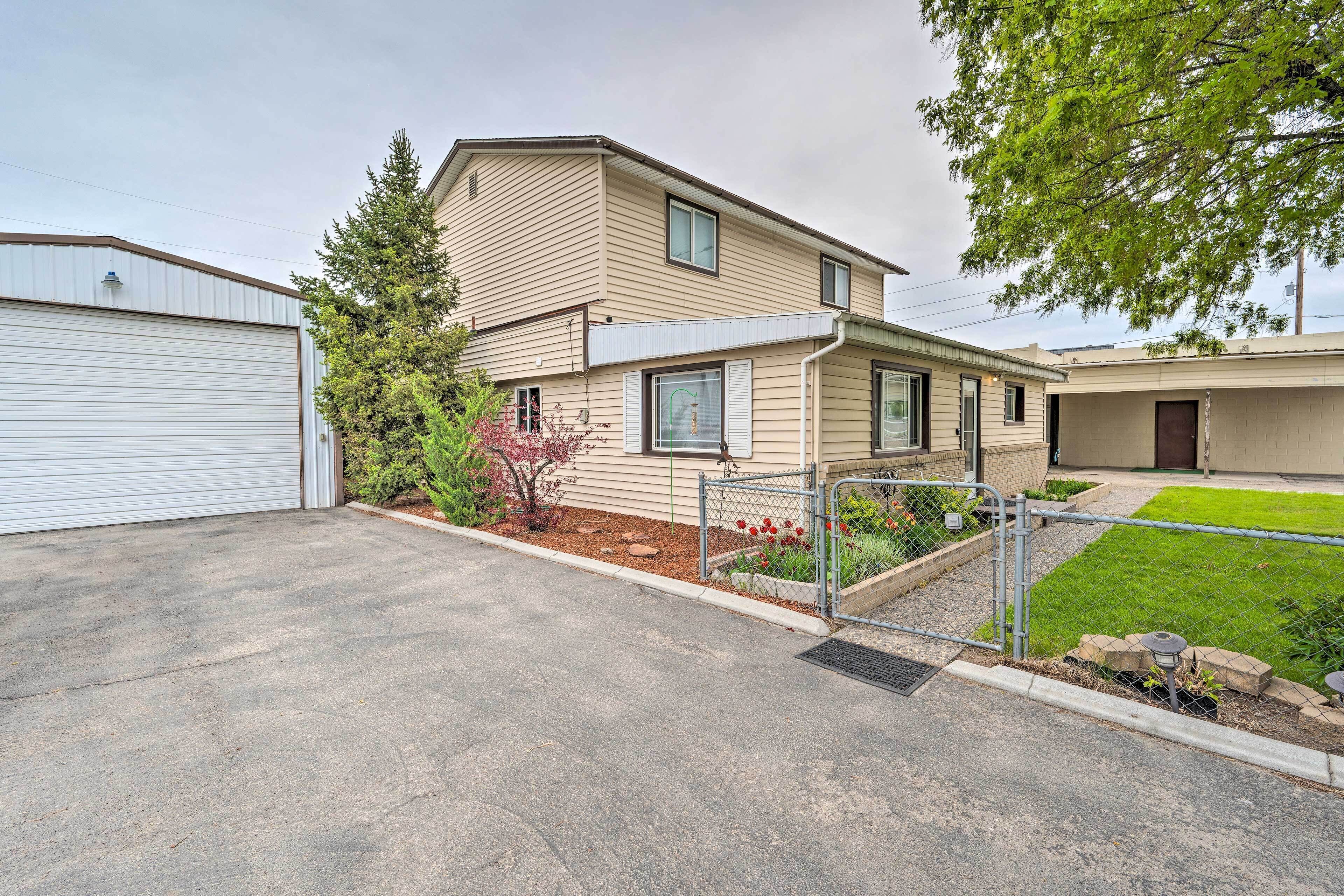 A two-story residential building with a garage, a fenced yard, and a well-maintained lawn.