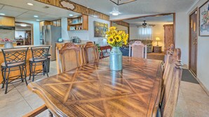 A dining area with a large wooden table, four chairs, and a vase of sunflowers.