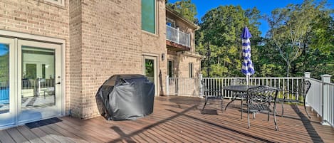 Une terrasse en bois avec des meubles d’extérieur, un barbecue et un espace patio couvert.