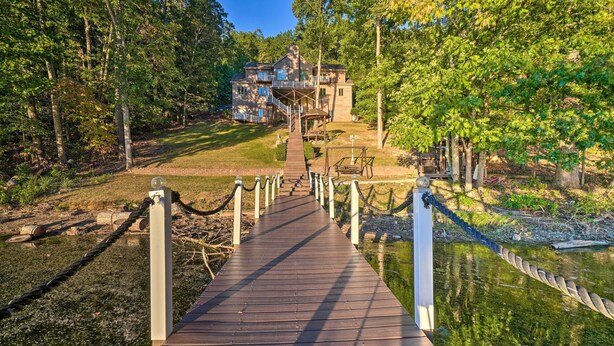 A wooden deck leading to a house surrounded by trees. - Luxe Lake Chickamauga Retreat w/ Boat Dock! (Harrison)