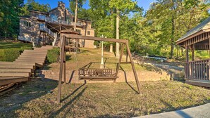 A wooden swing set in a backyard with a house in the background. - Luxe Lake Chickamauga Retreat w/ Boat Dock! (Harrison)