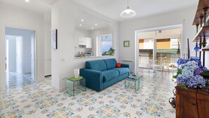 A spacious living room with a blue sofa, a glass coffee table, and a patterned floor. - Casa Maridea in Sorrento (Sorrento)