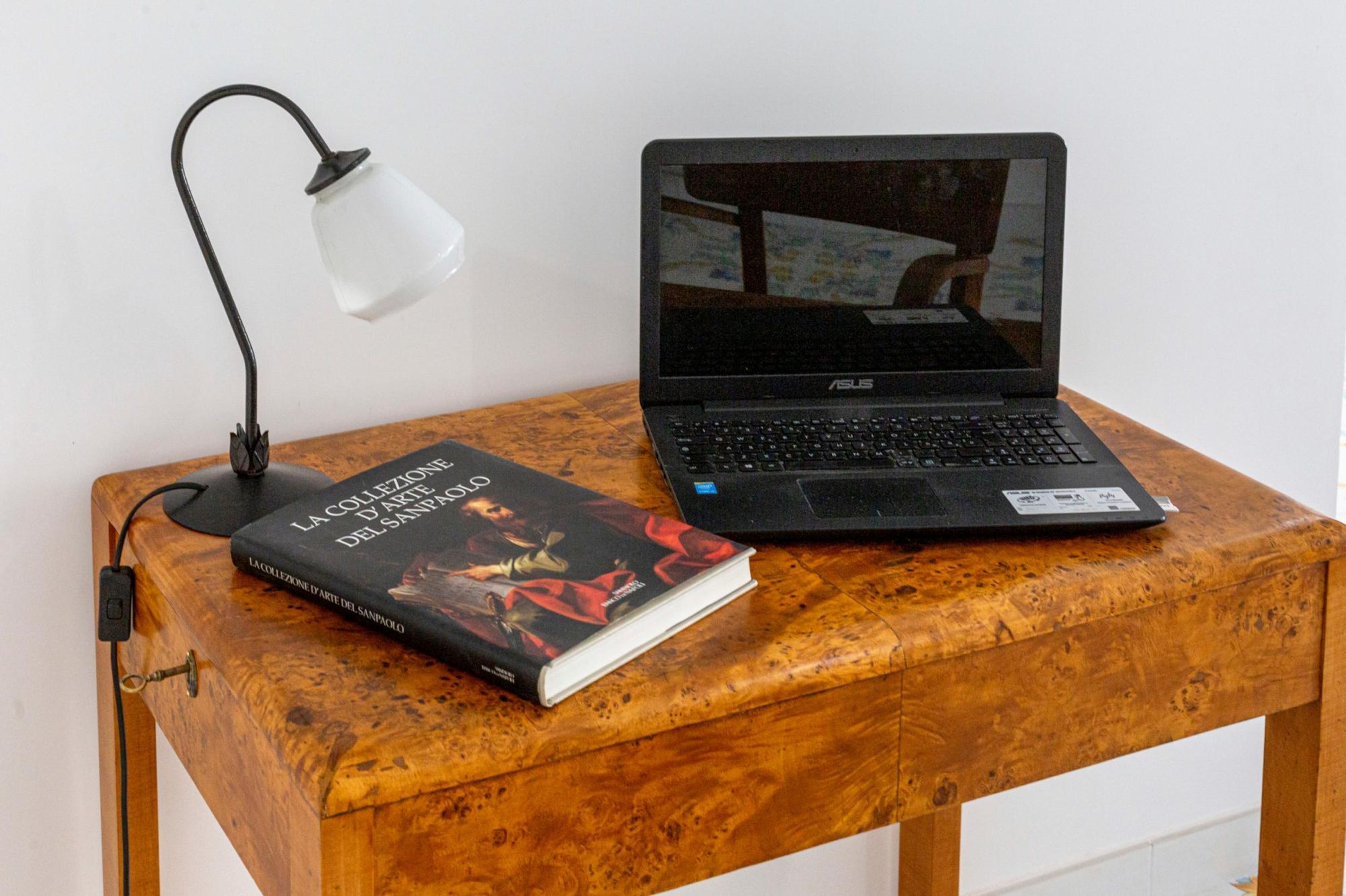 A wooden table with a laptop and a book.