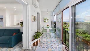 A modern living room with a sofa, dining table, chairs, and a balcony with a view. - Casa Maridea in Sorrento (Sorrento)