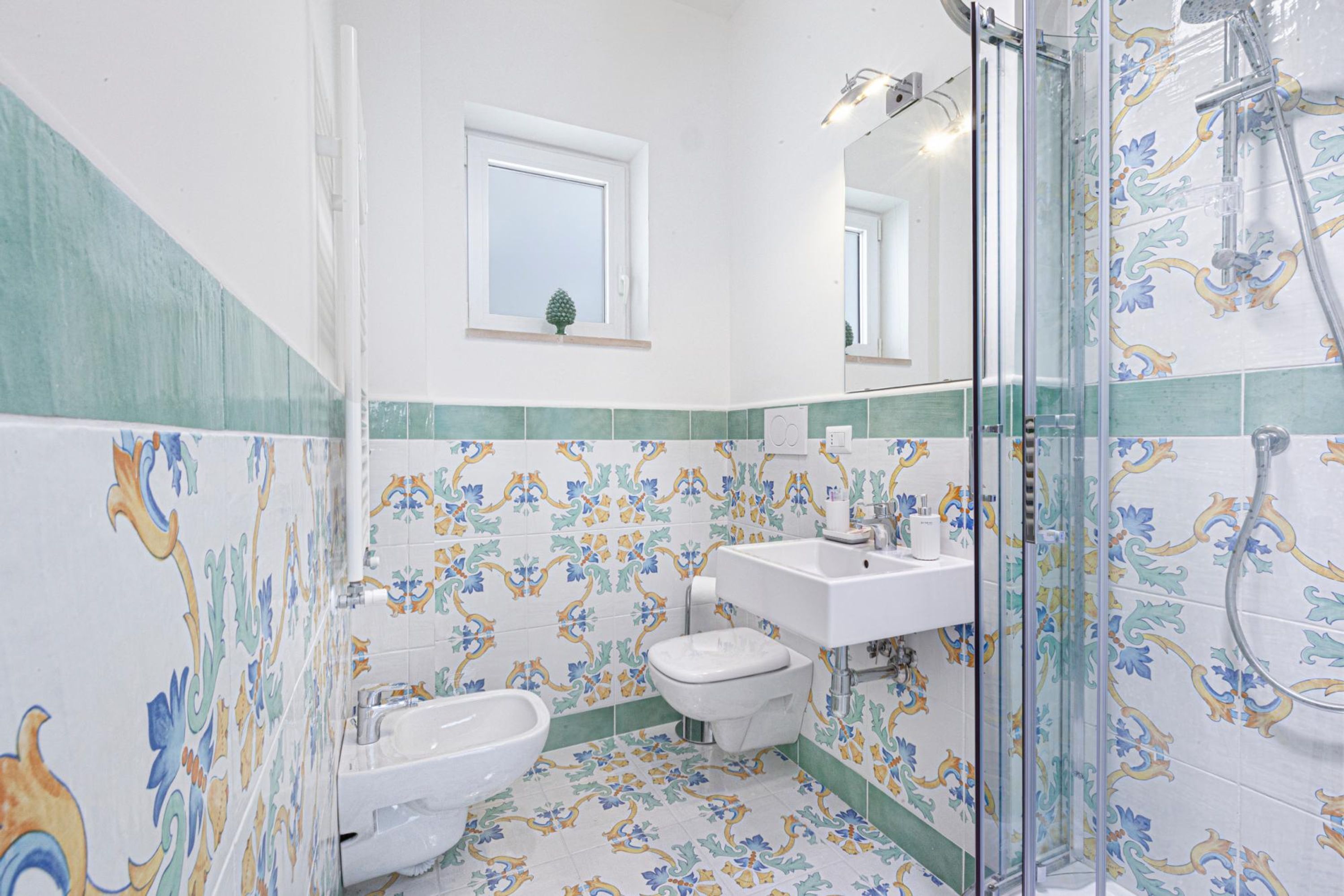 A bathroom with a toilet, bidet, sink, and shower.