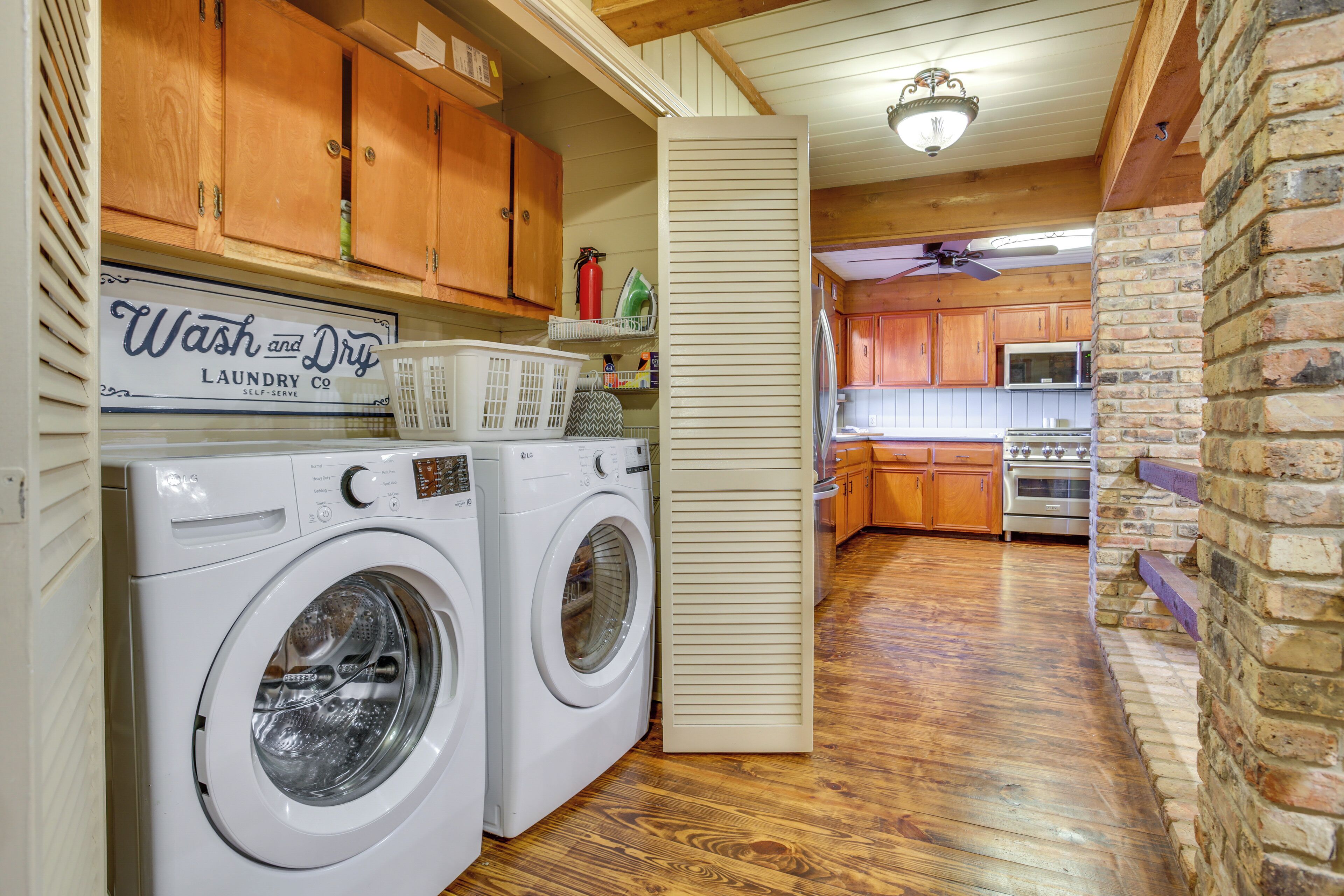 A laundry area with two washing machines, wooden cabinets, and a sign for a laundry service.