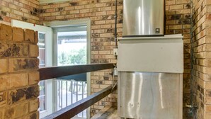 Een keuken met een roestvrijstalen koelkast, een bakstenen muur en een houten balustrade.
