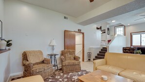 A living room with a patterned armchair, a sofa, a coffee table, and a staircase leading to an upper level. - Spacious Minneapolis Home Rental: 8 Mi to Downtown (Richfield)