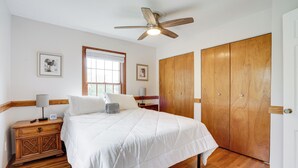 A bedroom with a bed, wooden wardrobe, nightstand, ceiling fan, and framed pictures on the wall. - Spacious Minneapolis Home Rental: 8 Mi to Downtown (Richfield)