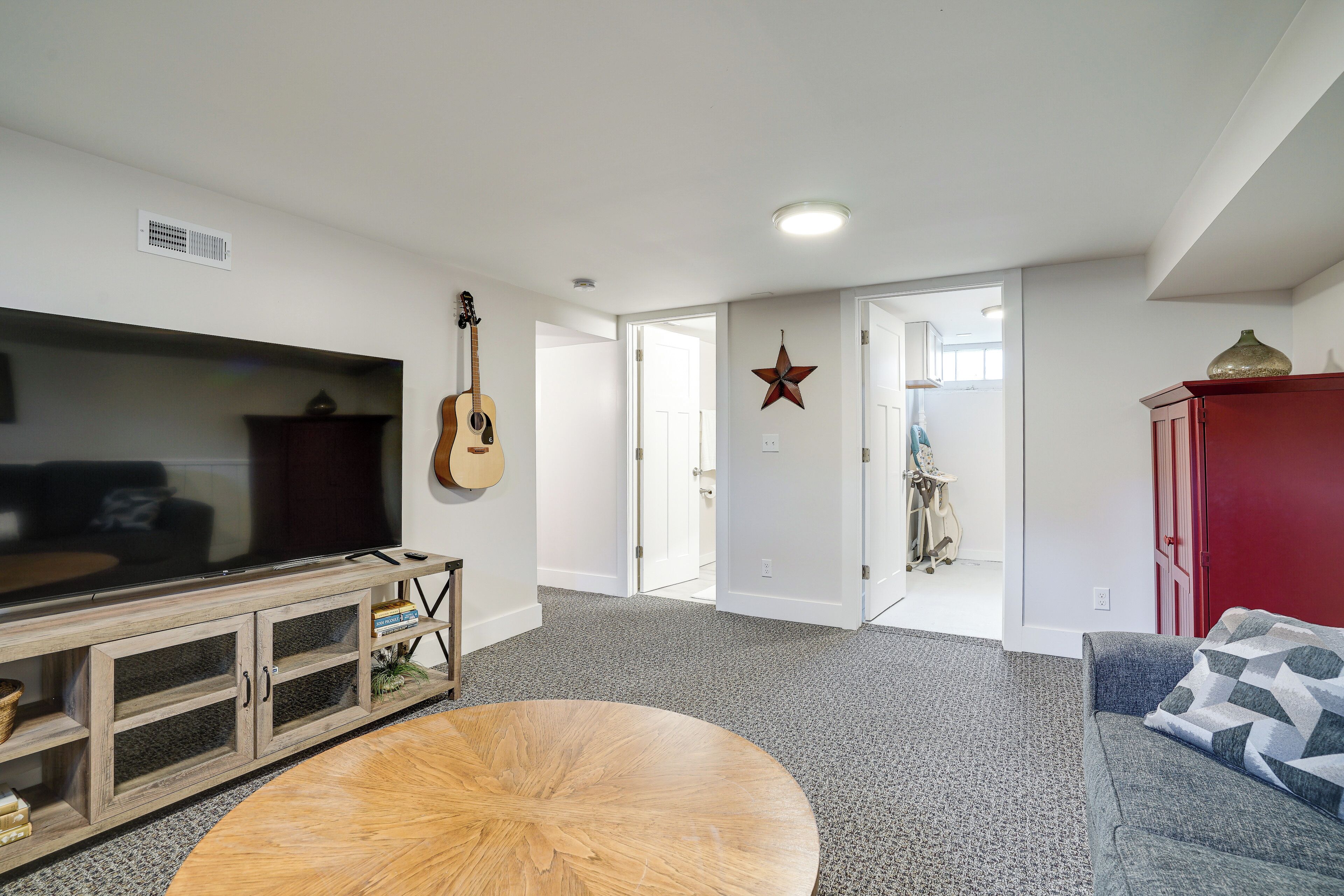 Una sala de estar con televisor, mueble de madera y una guitarra.