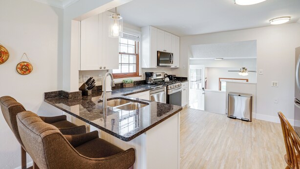 A modern kitchen with white cabinets, a granite countertop, and stainless steel appliances. - Spacious Minneapolis Home Rental: 8 Mi to Downtown (Richfield)