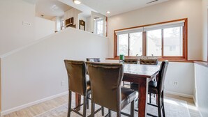 A dining area with a wooden table and leather chairs, a window with blinds, and a staircase leading to an upper level. - Spacious Minneapolis Home Rental: 8 Mi to Downtown (Richfield)