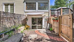 A house with a front porch, a wooden fence, and a brick pathway leading to the door. - Garden-level Millburn Apt - Walk to Transit! (Millburn)