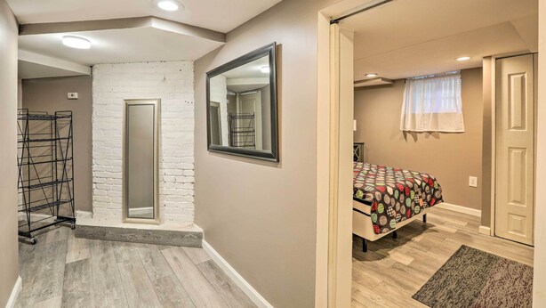 A bedroom with a bed, a window with curtains, a door, and a mirror on the wall. - Garden-level Millburn Apt - Walk to Transit! (Millburn)