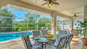 An outdoor patio with a pool, seating, and ceiling fans.