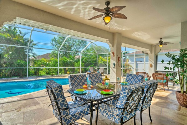 An outdoor patio with a pool, seating, and ceiling fans.